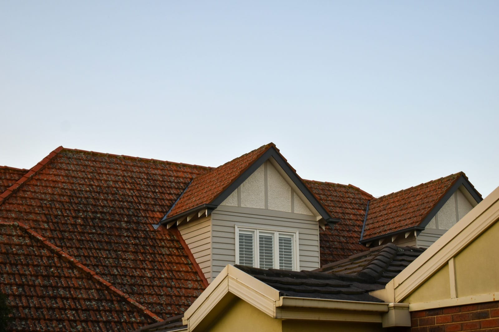 Two-person roofing crew working on a residential pitched roof with new shingles installed